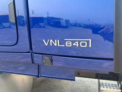 Volvo VNL840 badge on blue truck door showing VNL840 text and reflection of surroundings.