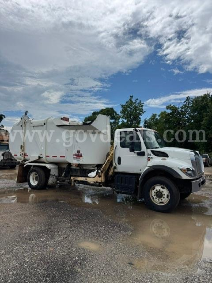 Garbage truck side view with a white International HV607 cab and rear municipal body. Visible text on image includes faint watermark 'www.govdeals.com' across the side; no other legible labels.