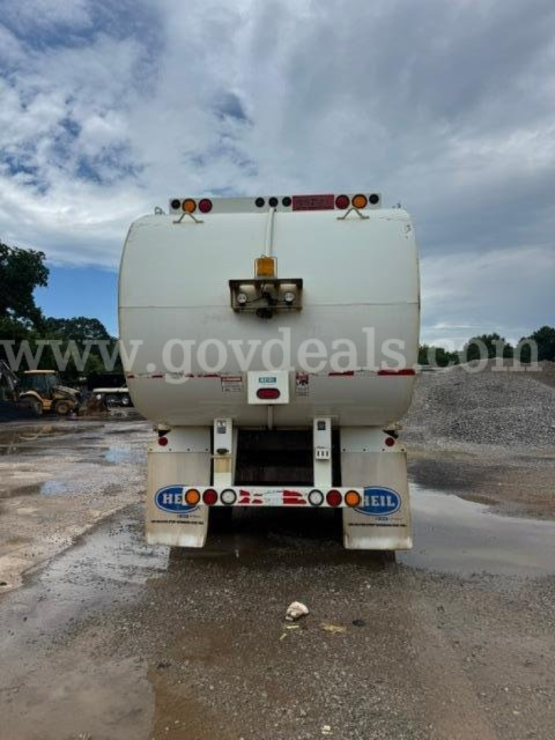Rear view of a white International HV607 truck tank showing taillights and bumper signage.