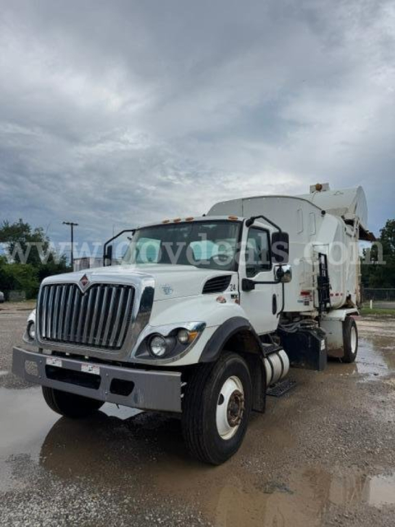International HV607 garbage truck showing front view with large grille, white cab, and rear compactor unit.