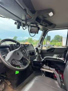 Truck cab interior showing steering wheel, dashboard, gear shifter, and overhead display screen in a 2021 International HV607.