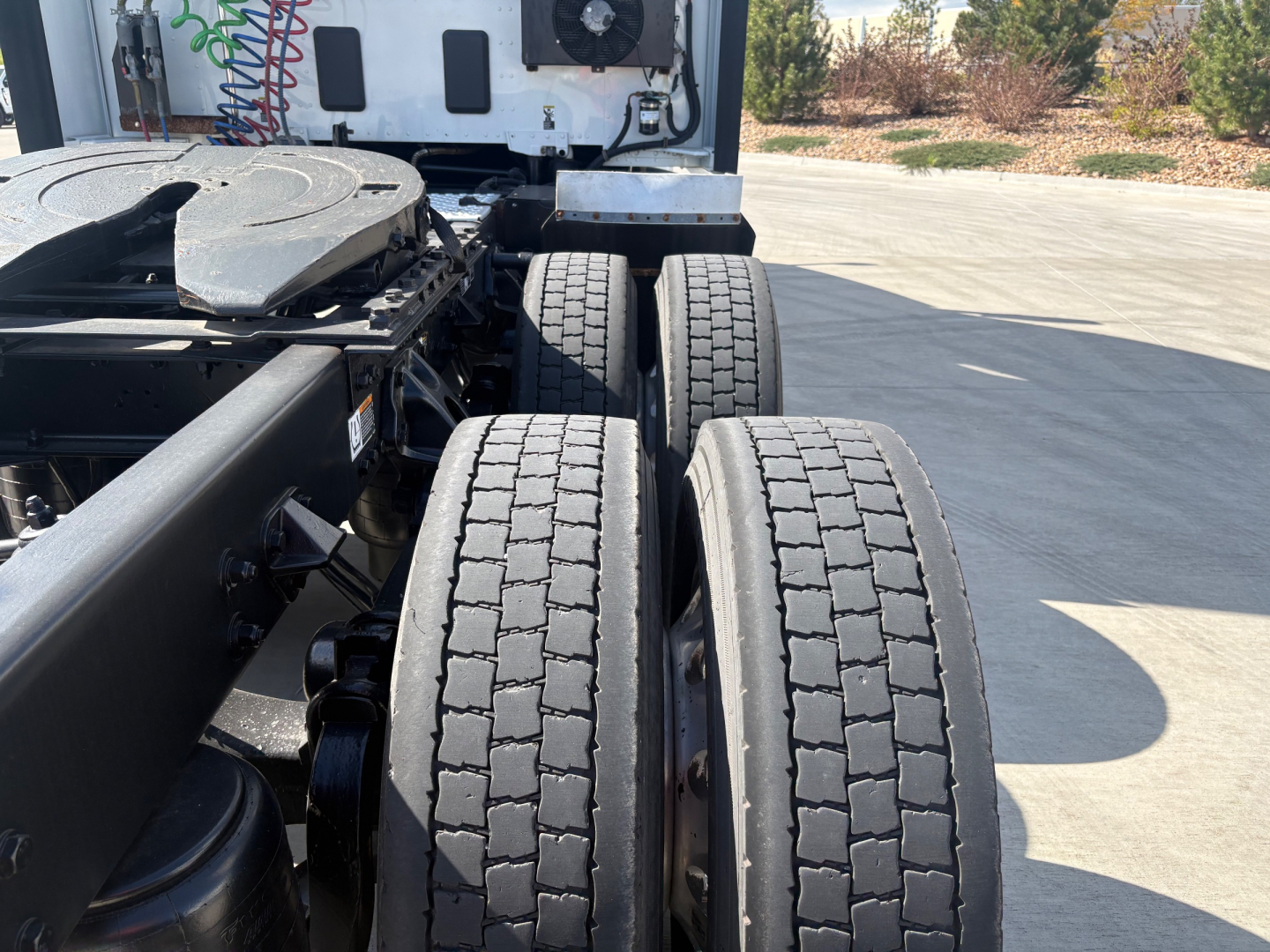 Kenworth T680 chassis with dual rear axles and tires showing view from side; cab area and fifth wheel visible in background.