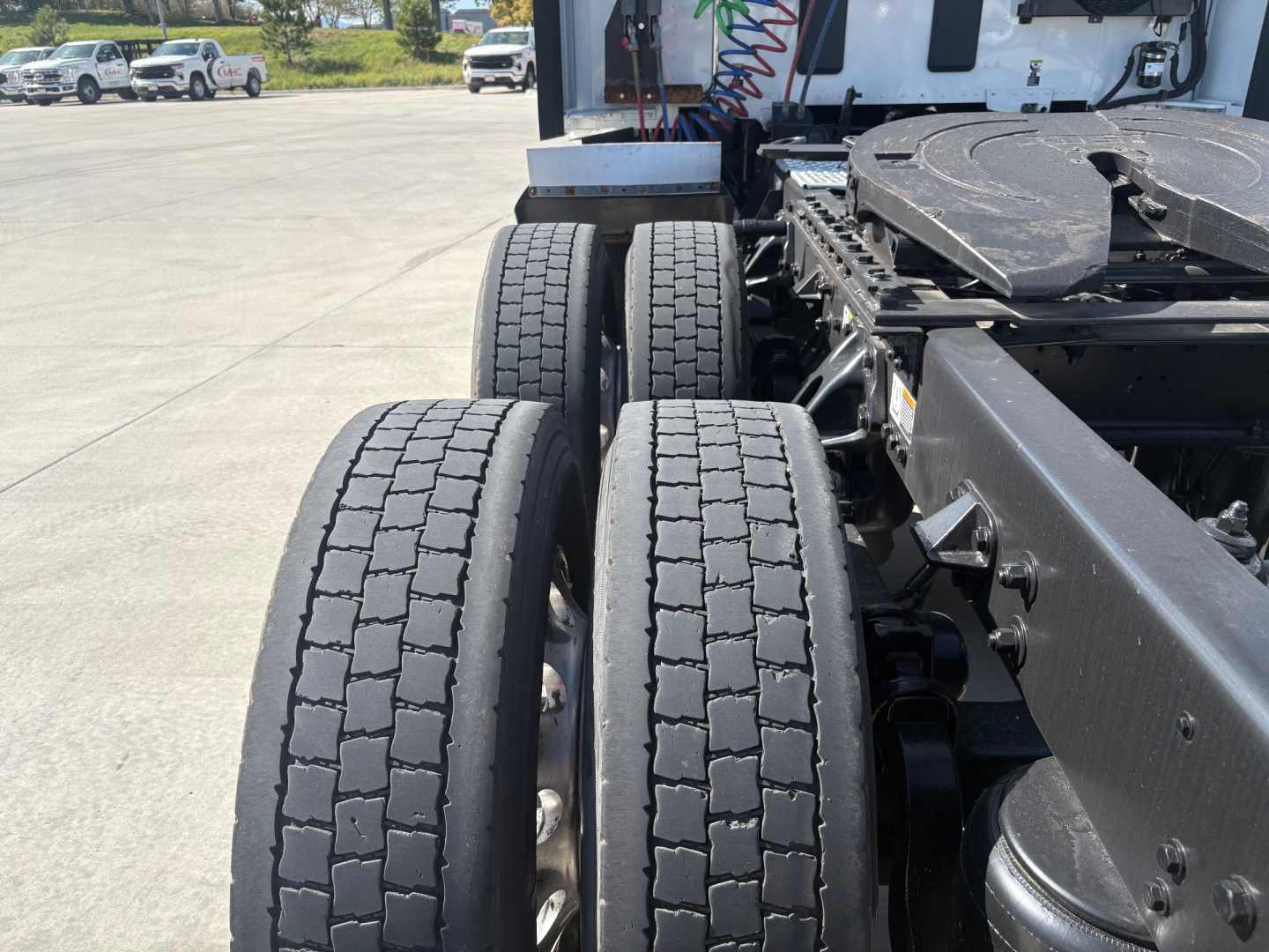 Kenworth T680 rear view showing dual rear axles and tires with tread pattern, chassis frame, and parts of sleeper cab in background.