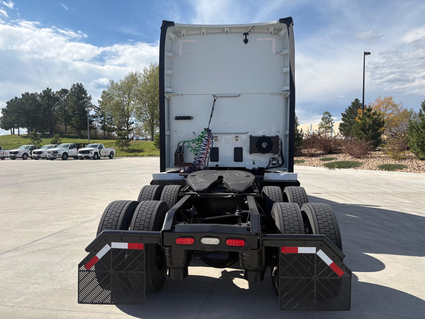 Kenworth T680 rear view showing fifth wheel, dual rear axles, and mud flaps with reflective trim.