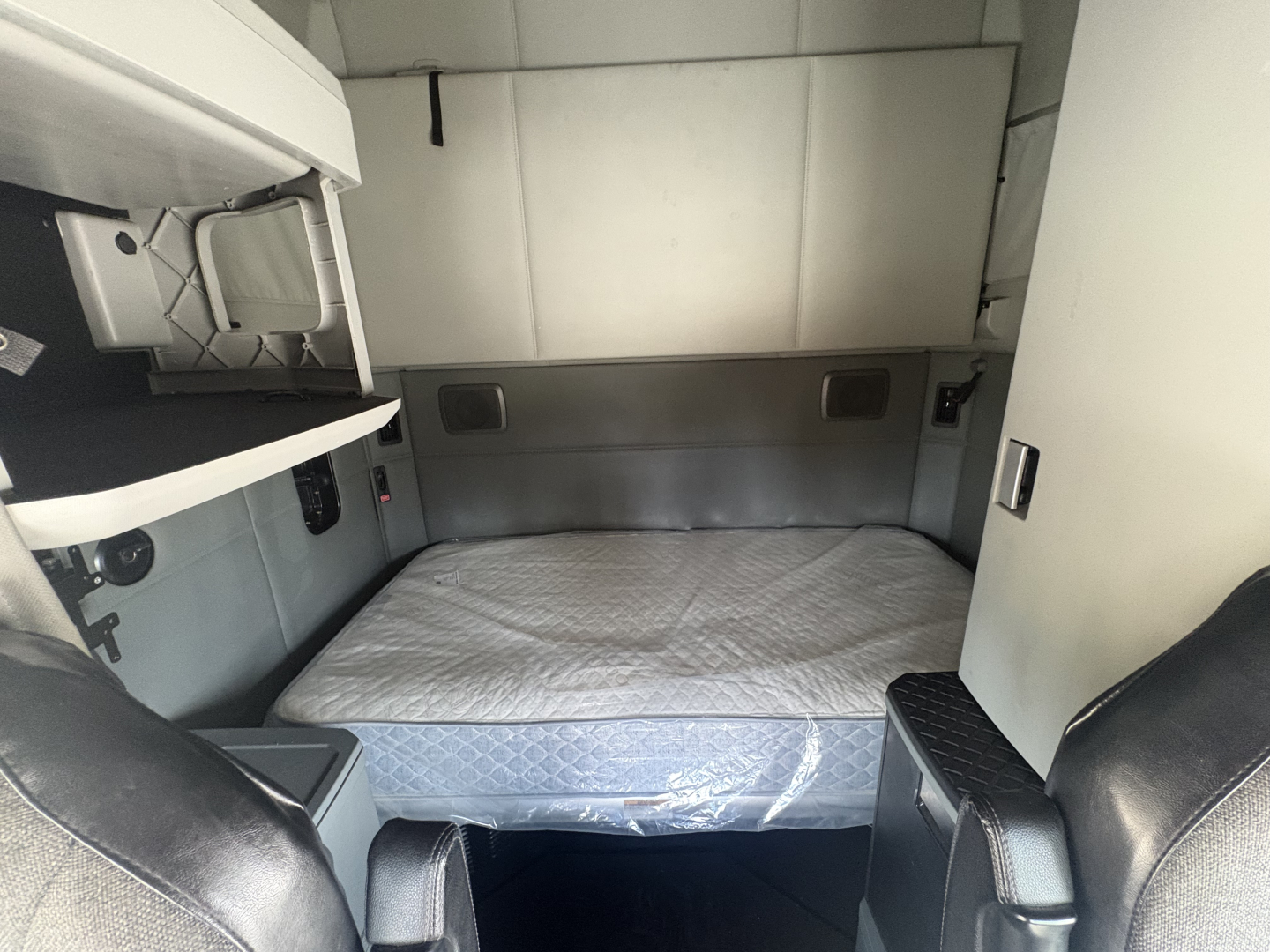 Kenworth T680 sleeper cab interior showing bed and cabin storage area.