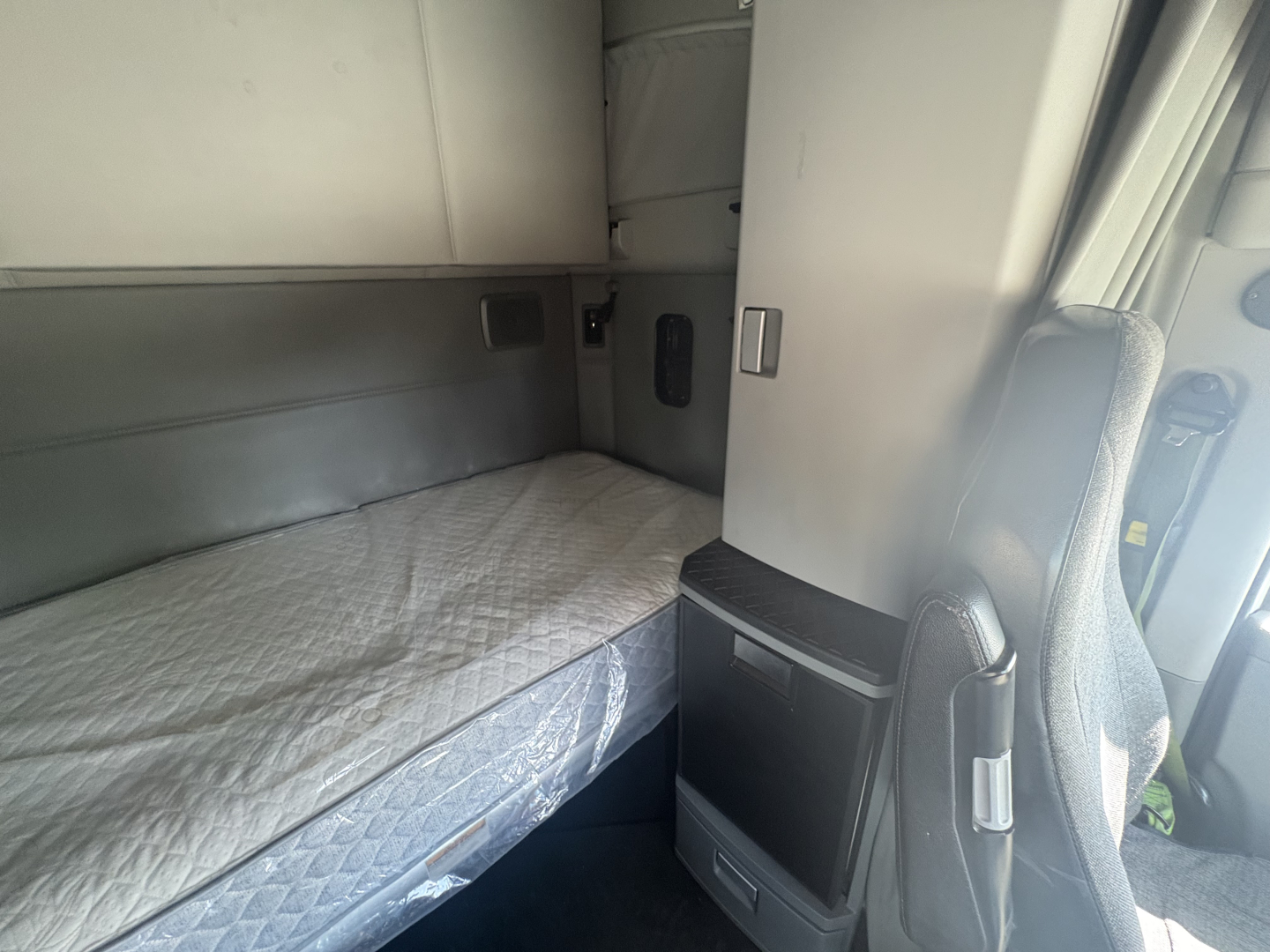 Interior sleeper cab of a 2021 Kenworth T680 showing bunk bed with mattress and side cabinets.