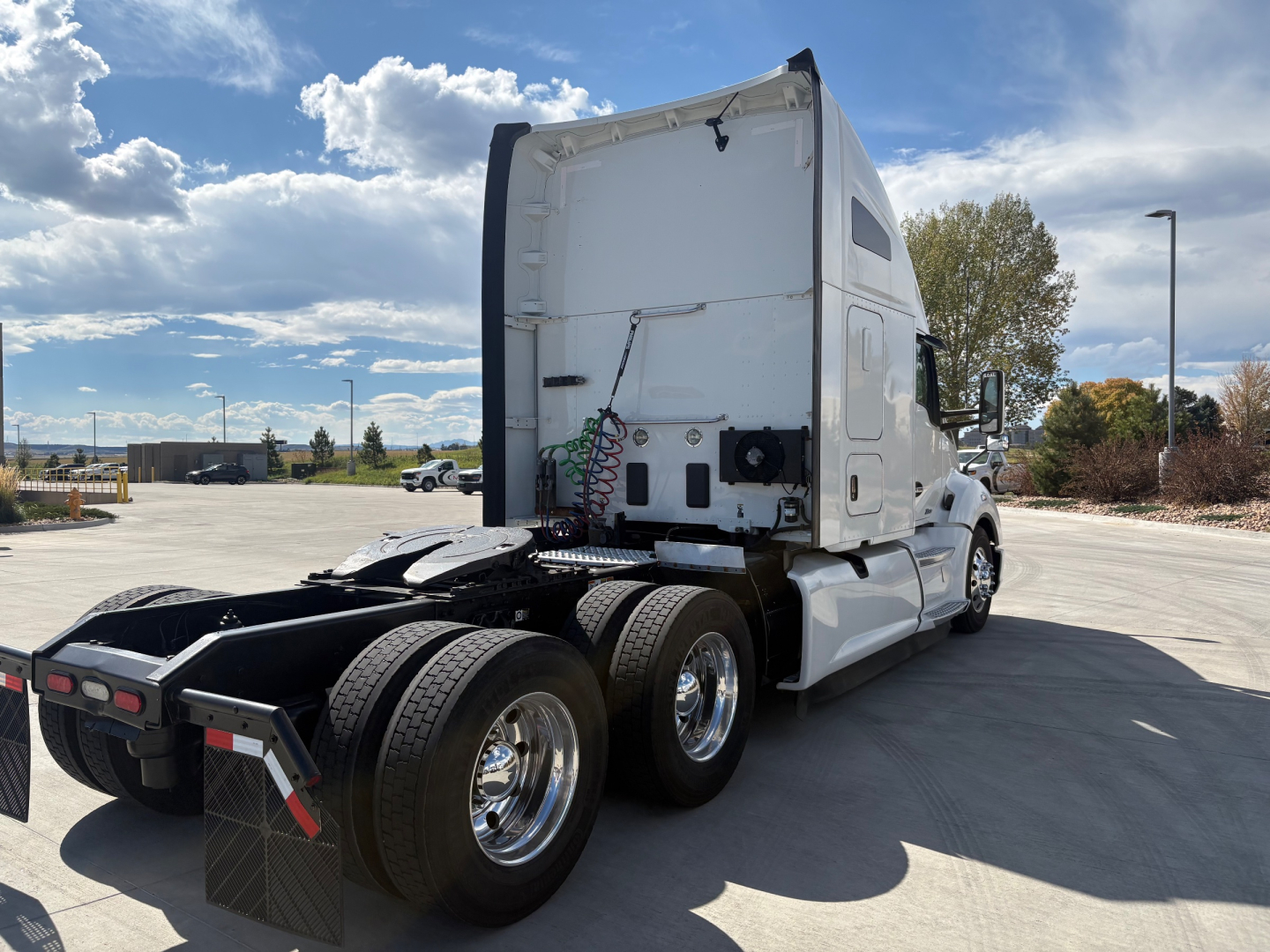 Kenworth T680 tractor in white, rear/side view showing fifth wheel area, fuel lines, and dual rear axles.