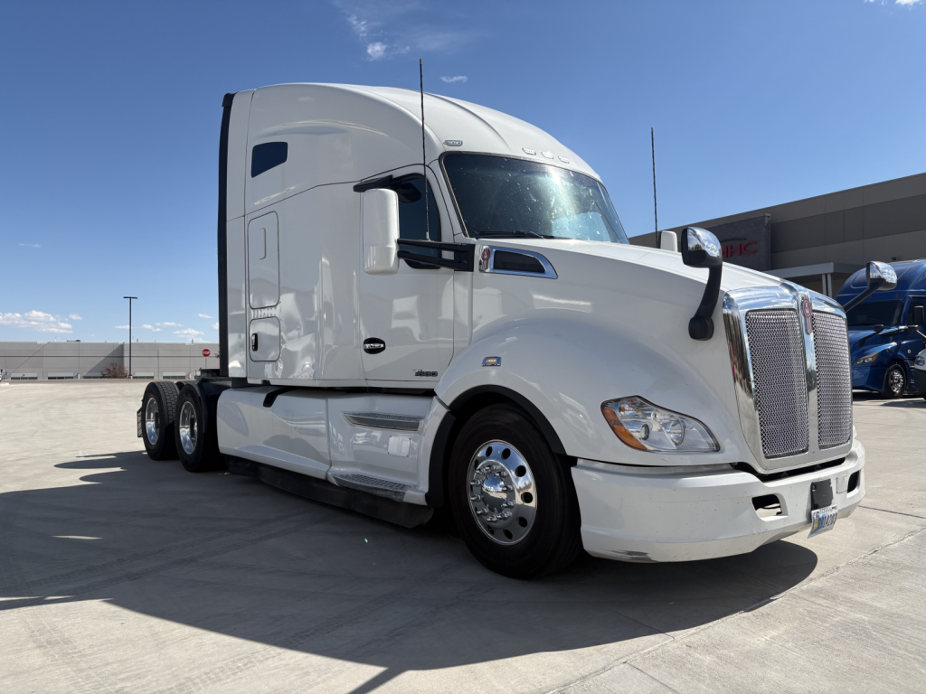 Kenworth T680 tractor seen in white, side view with sleeper cab, dual rear axles, chrome wheels. No visible text on the body aside from reflections.