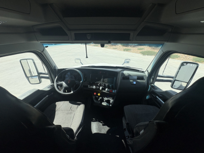 Kenworth T680 cab interior showing steering wheel, dashboard, and front seats; windshield and side mirrors visible.
