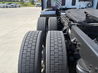 Kenworth T680 rear view showing dual rear axles and tires with tread pattern, chassis frame, and parts of sleeper cab in background.