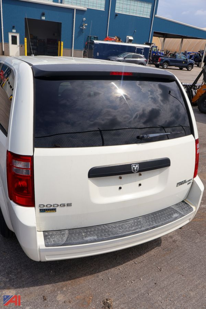 Rear view of a white 2009 Dodge Grand Caravan minivan with tinted rear window and chrome bumper step.