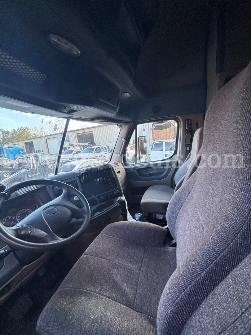 Cab interior of a 2012 Freightliner Cascadia 125 truck showing driver seat, steering wheel, dashboard, and front passenger area.