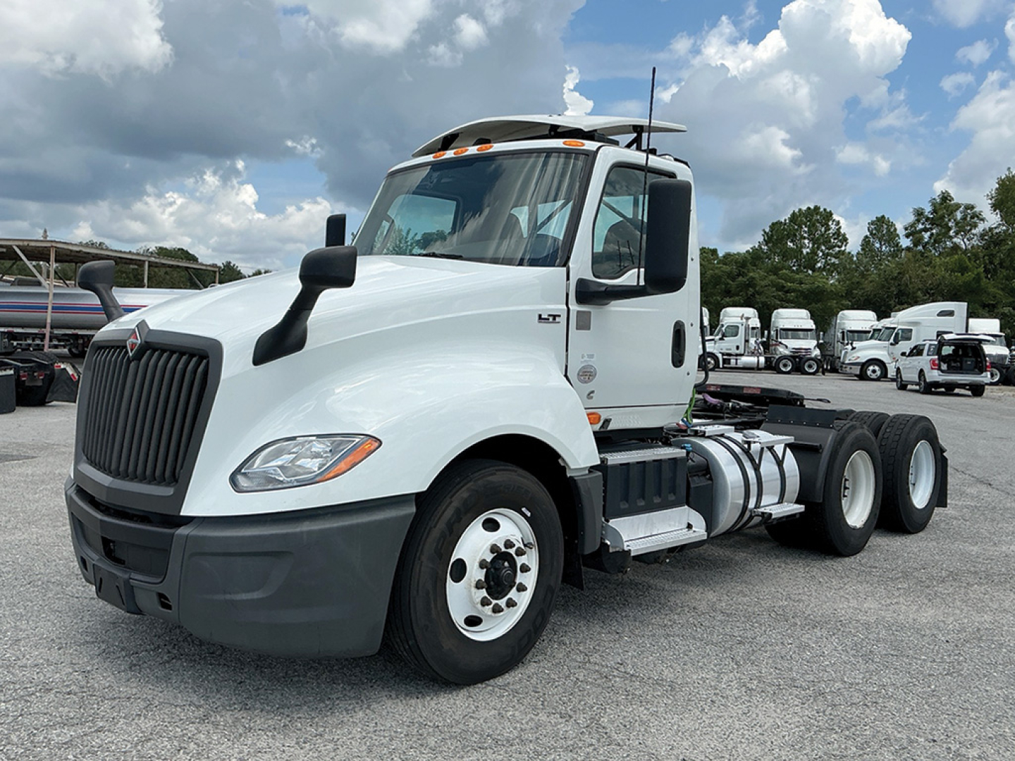 Truck cab and chassis showing International LT625 daycab with white paint and dual rear axles in a dealership lot.