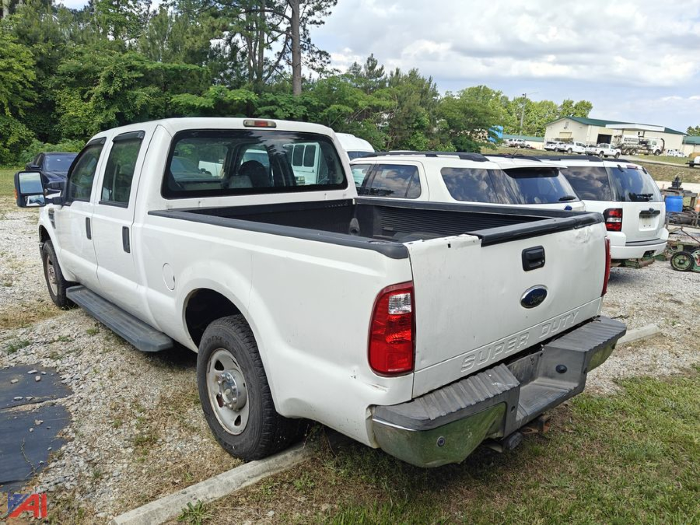 Ford F-250 Super Duty pickup rear three-quarter view showing bed and tailgate with dual rear wheels and white paint.