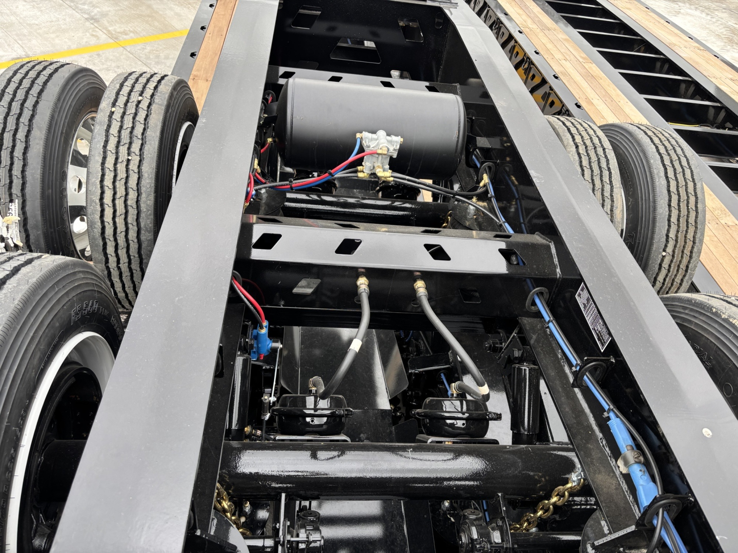 Trailer dolly chassis with dual rear axles, hydraulic hoses, and control components visible; frame, axles, and winch area show electrical wiring and pneumatic lines.