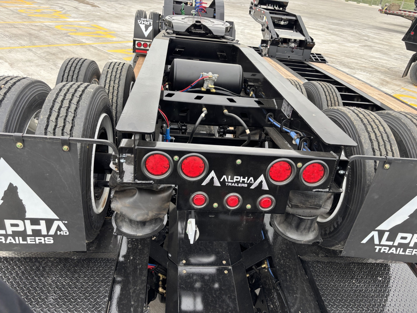 Rear view of a black Alpha Trailers dolly trailer chassis showing dual rear axles, taillights, and hydraulic components with Alpha Trailers branding.