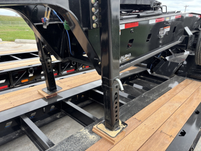 Alpha A80JD Jeep Dolly trailer frame showing adjustable support legs, wooden deck planks, and hydraulic components with welded steel rails.