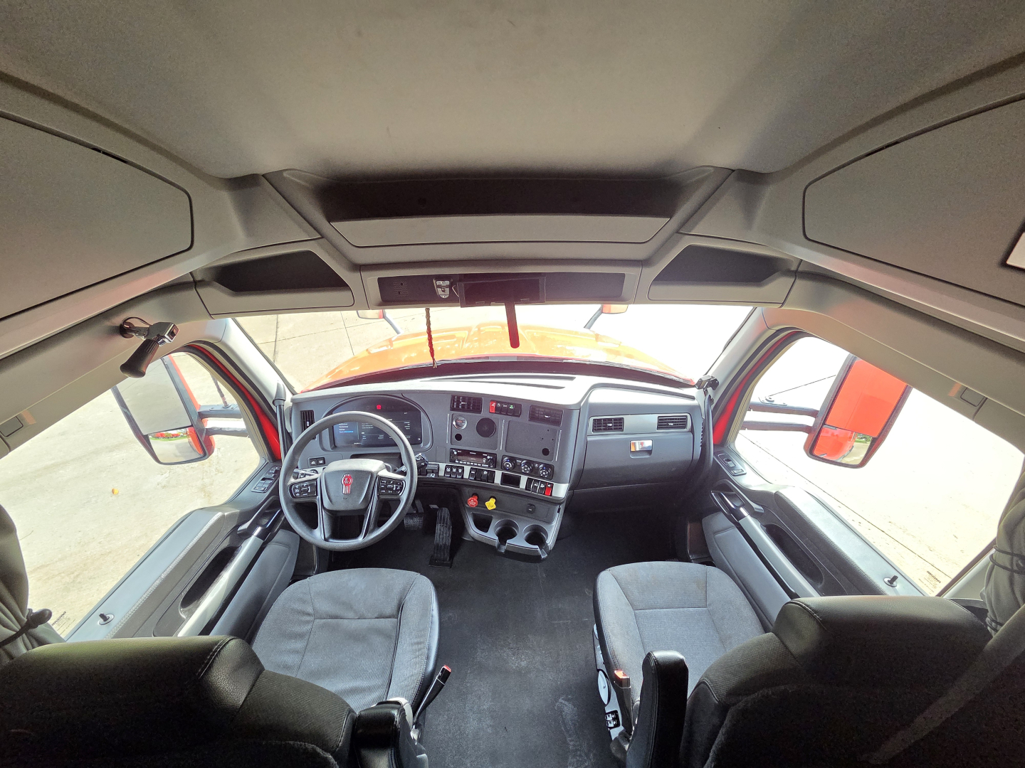 Truck cab interior view from driver seat to dashboard with steering wheel, instrument cluster, and center console visible.