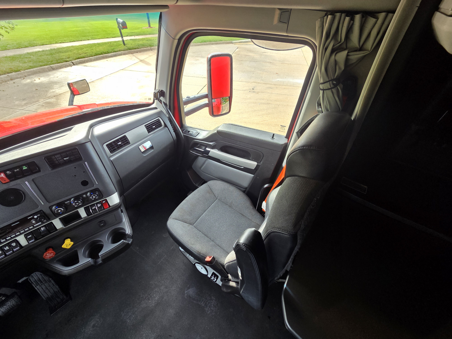 Kenworth T680 cab interior showing driver seat and dashboard with steering wheel and control panels.