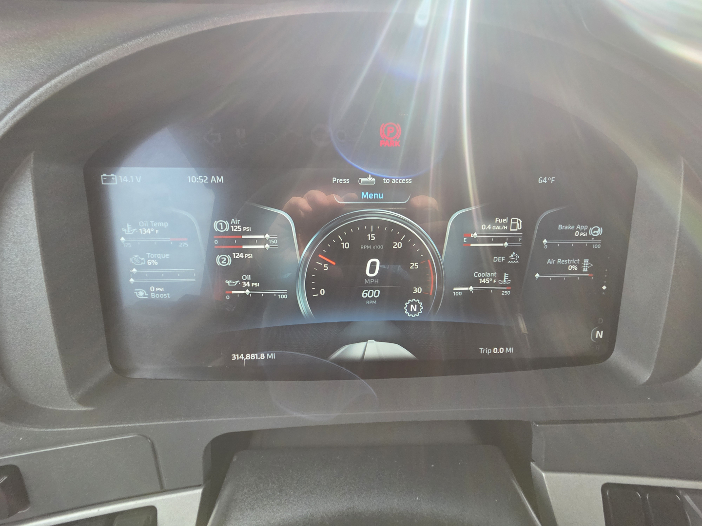 Kenworth T680 dash cluster in driver’s view with digital gauge display and warning light visible in center; shows odometer, speedometer, and multiple vehicle readouts.