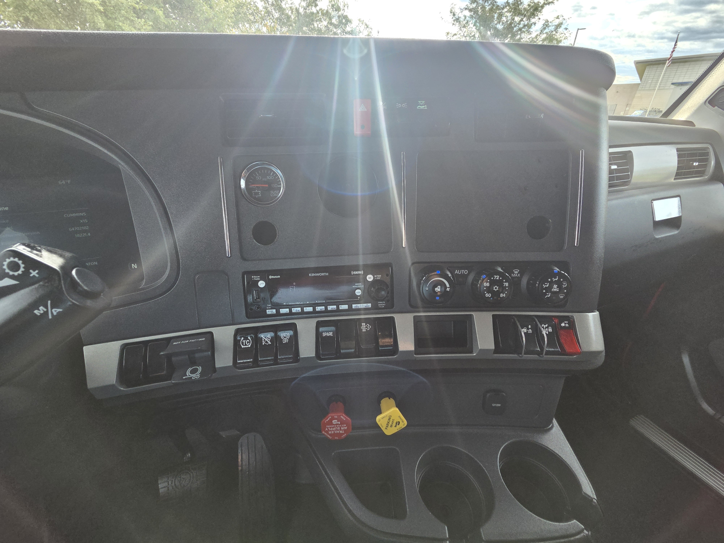 Dashboard view of 2022 Kenworth T680 interior showing gauges, controls, cup holders, and center console.