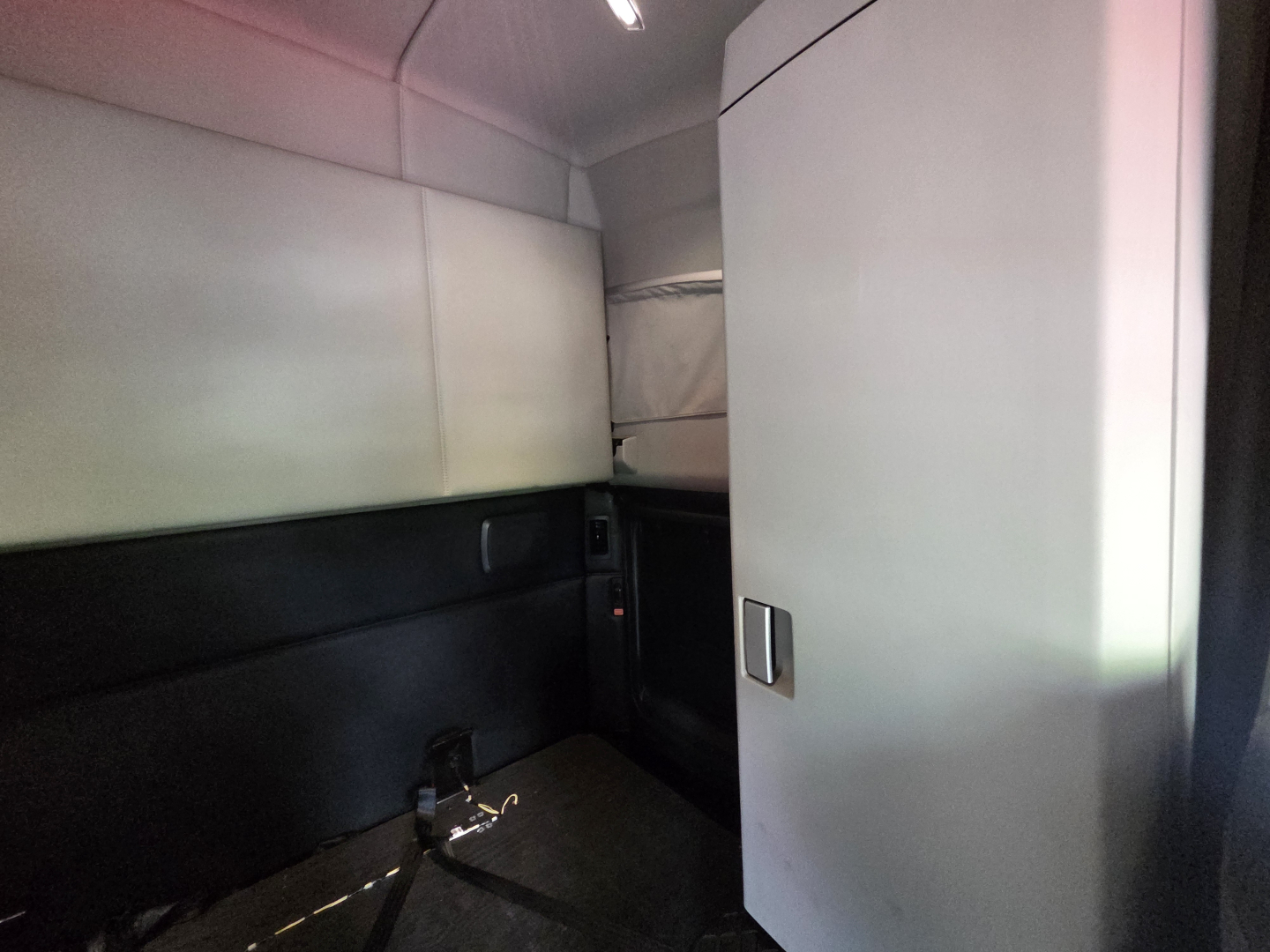 Kenworth T680 interior sleeper cab area with door panel and storage cabinet, showing limited view of the cabin front.