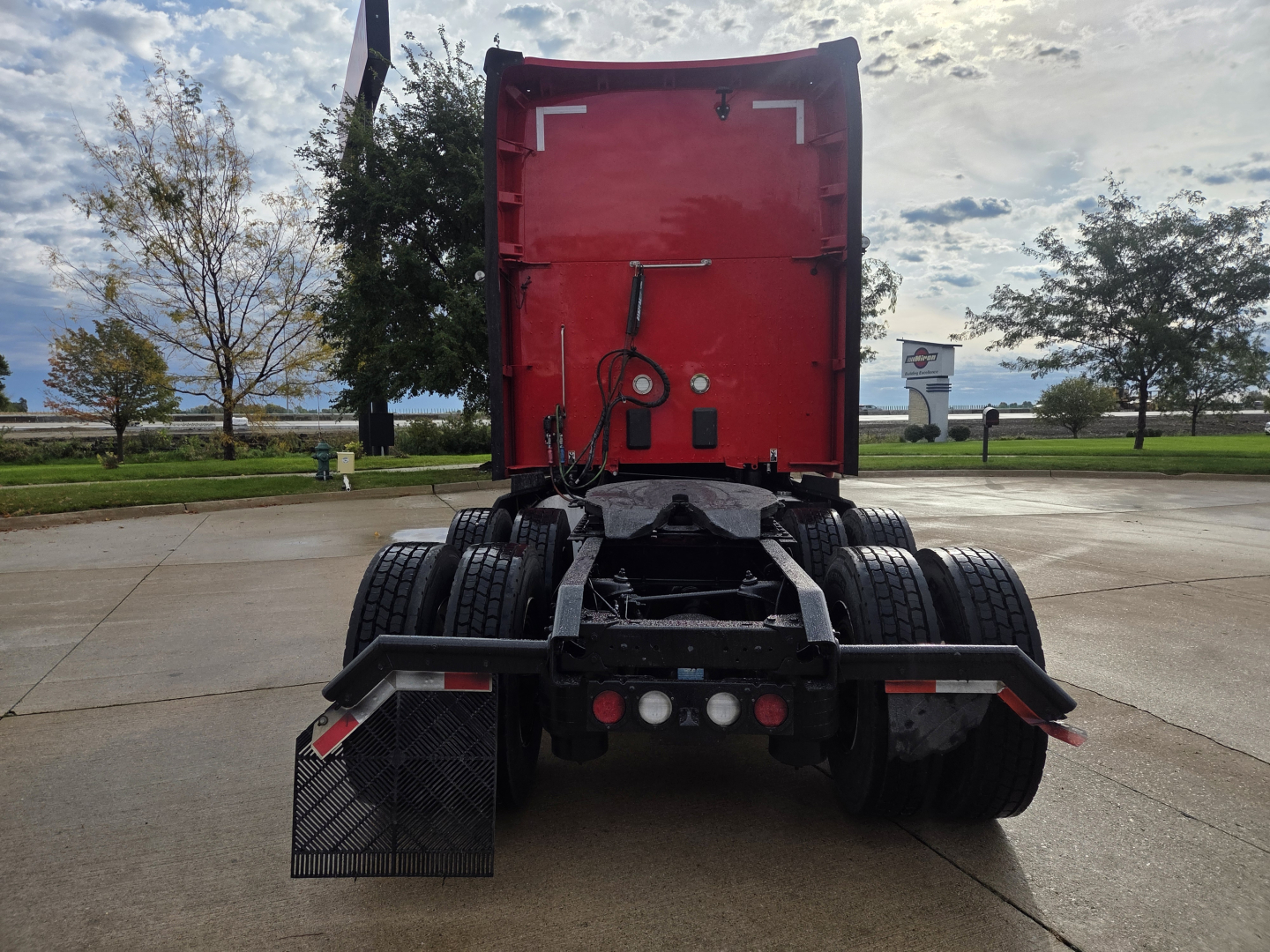 Kenworth T680 rear view showing red sleeper cab, dual rear axles, and trailer connections.