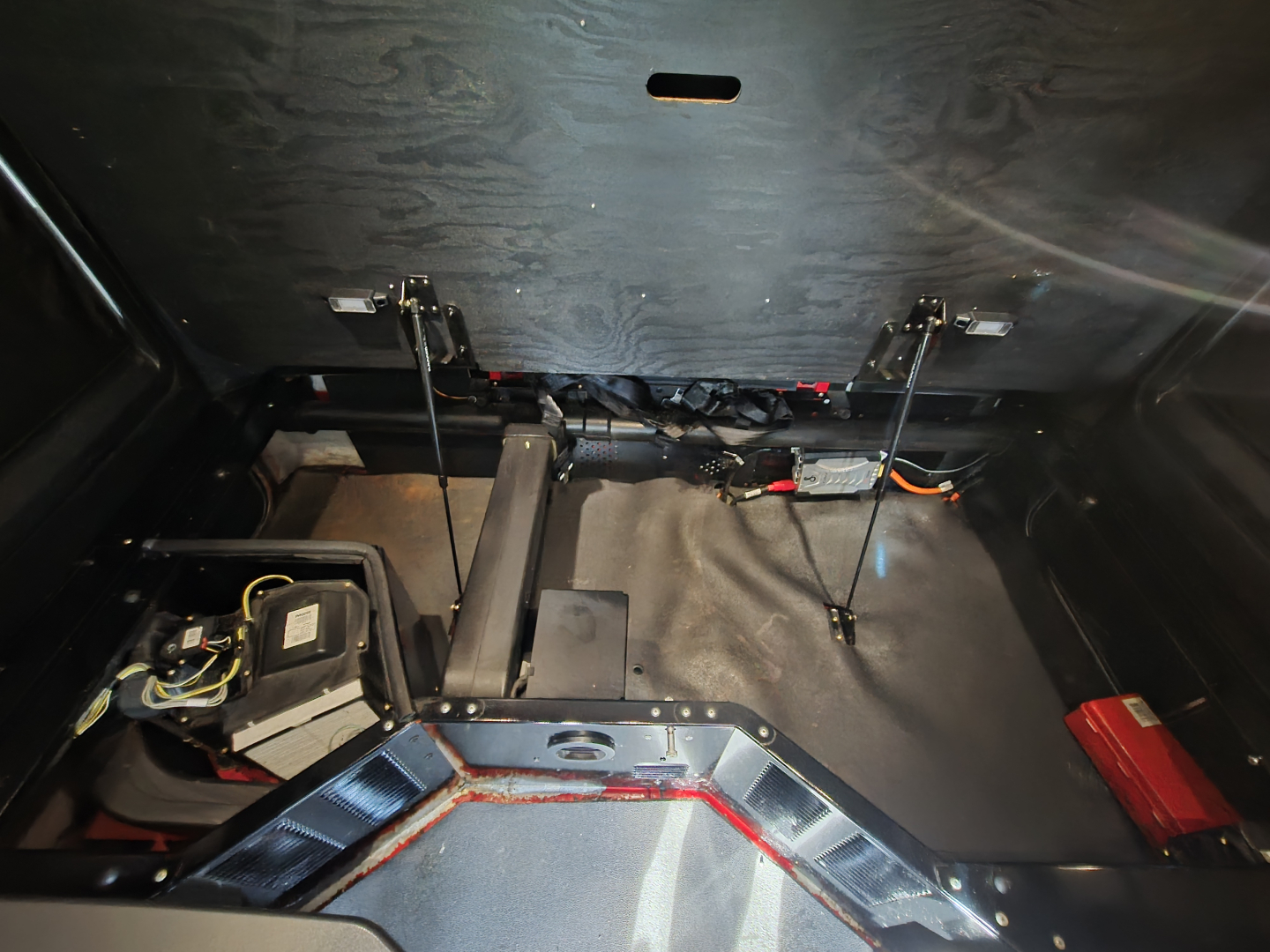 Kenworth T680 under-bunk area with battery, wiring, and frame components visible.