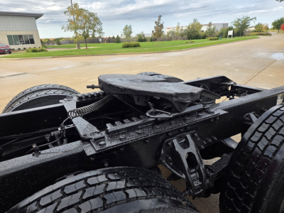 Vehicle chassis of a Kenworth truck showing frame rails, suspension components, and rear wheels; wet surfaces.