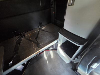 Interior sleeper cab area of a 2022 Kenworth T680 with a mounted small fridge or cabinet and a flat floor platform.