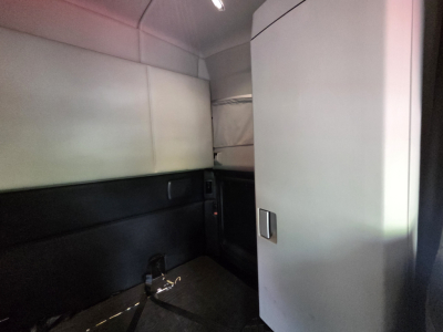 Kenworth T680 interior sleeper cab area with door panel and storage cabinet, showing limited view of the cabin front.