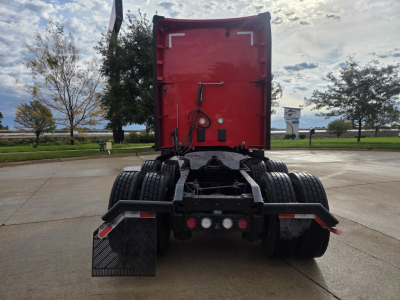 Kenworth T680 rear view showing red sleeper cab, dual rear axles, and trailer connections.