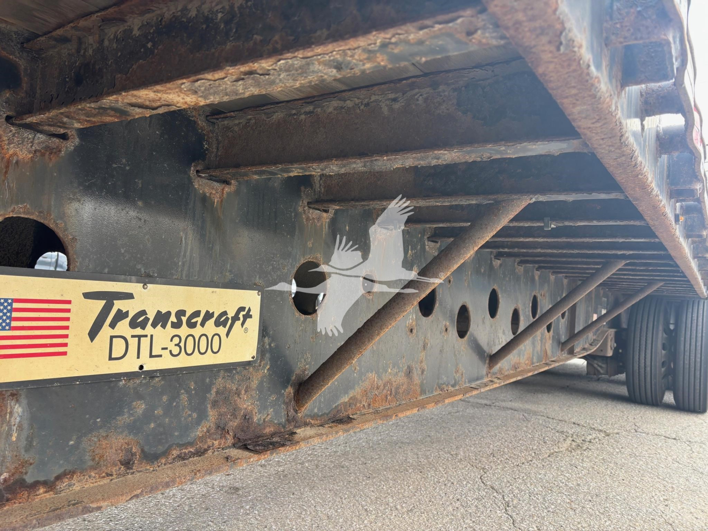 Transcraft DTL-3000 tag on trailer frame with rusted undercarriage and structural members visible.