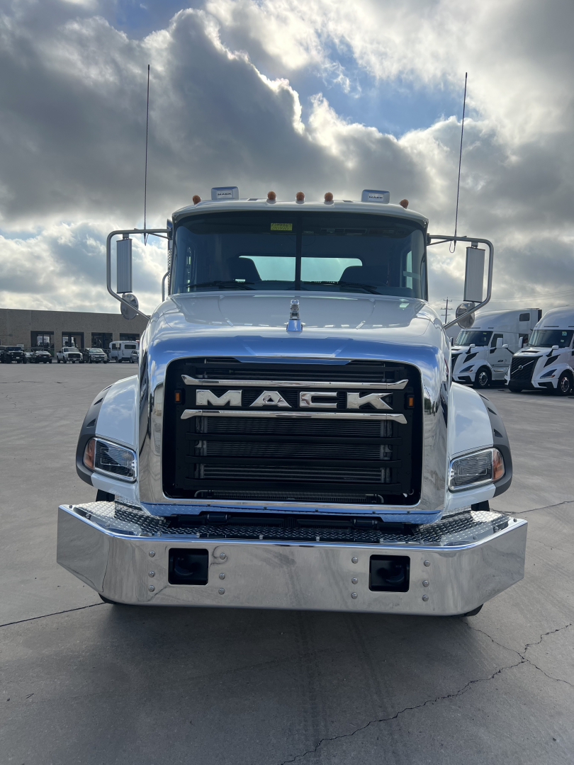 Front view of a white 2026 Mack GR64B cab and chassis truck showing large black grille with MACK letters, chrome bumper, and side mirrors.