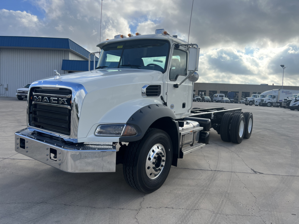 Mack GR64B cab and chassis truck in white with chrome bumper and grille, dual rear axles, daytime scene at a dealership.
