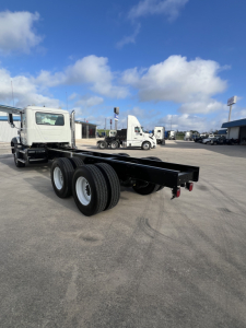Mack GR64B cab and chassis under clear sky, flatbed removed, showing rear dual rear wheels and chassis frame.