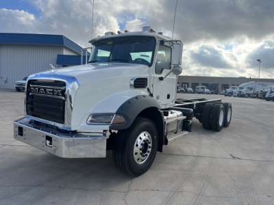 Mack GR64B cab and chassis truck in white with chrome bumper and grille, dual rear axles, daytime scene at a dealership.