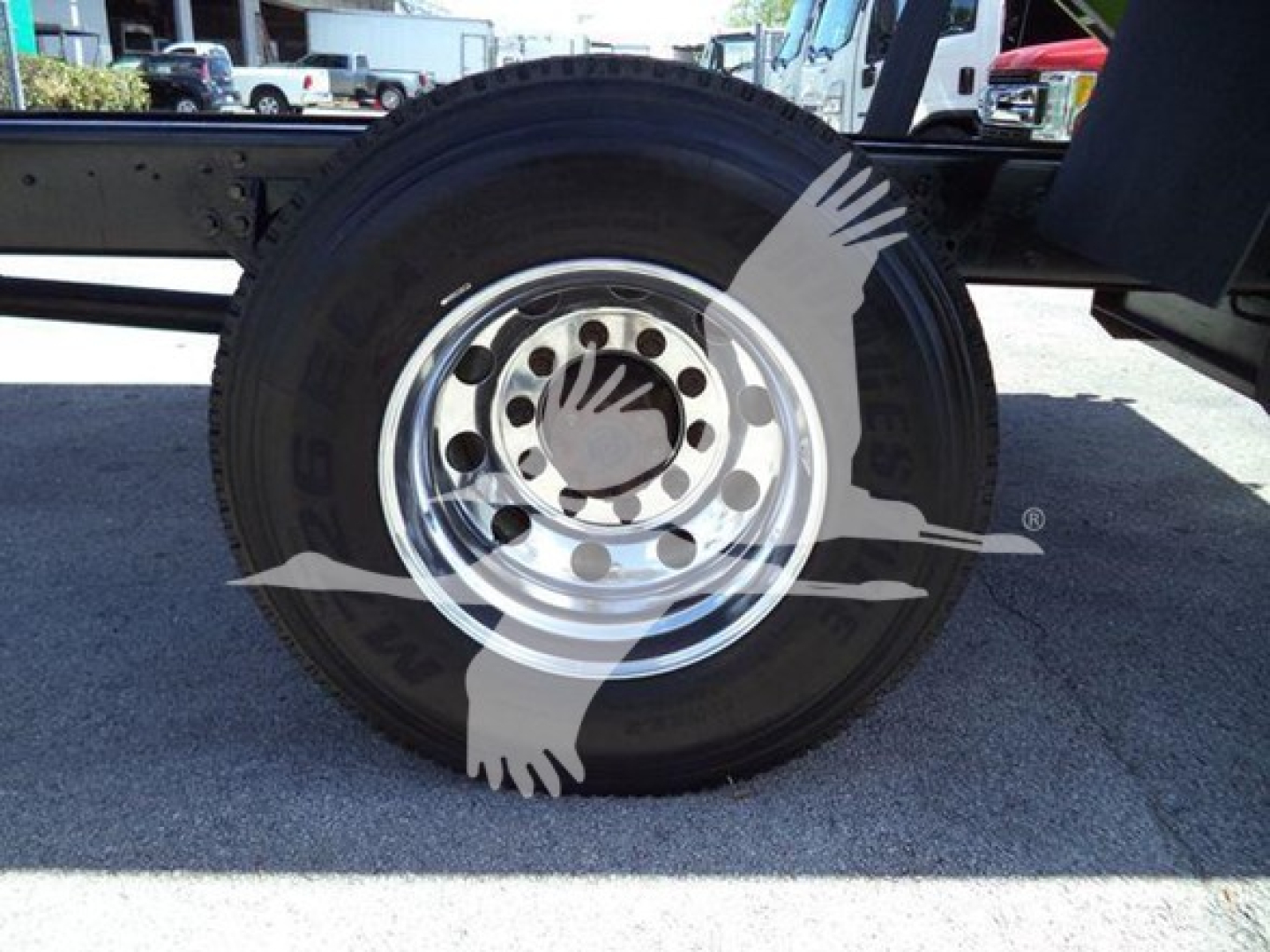 Truck wheel showing dual tires and chrome hub with seating; wheel well and frame visible.