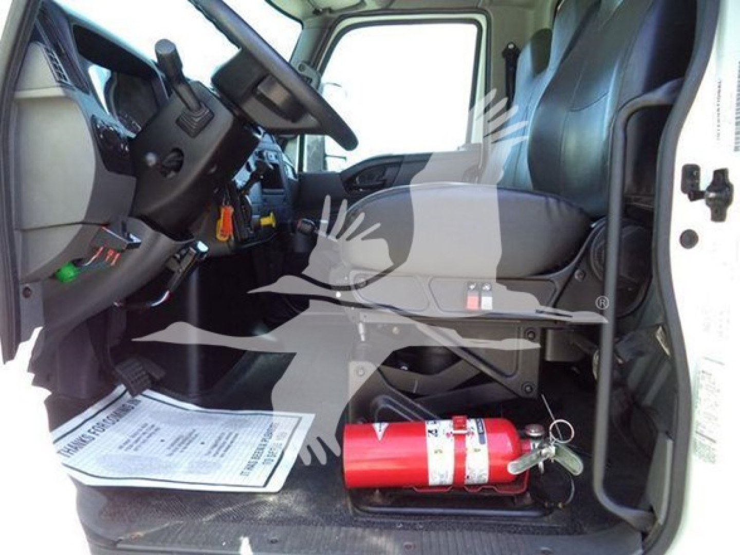 Interior cab view of a 2020 International MV dump truck showing steering wheel, driver's seat, dashboard, and a red fire extinguisher on the floor.