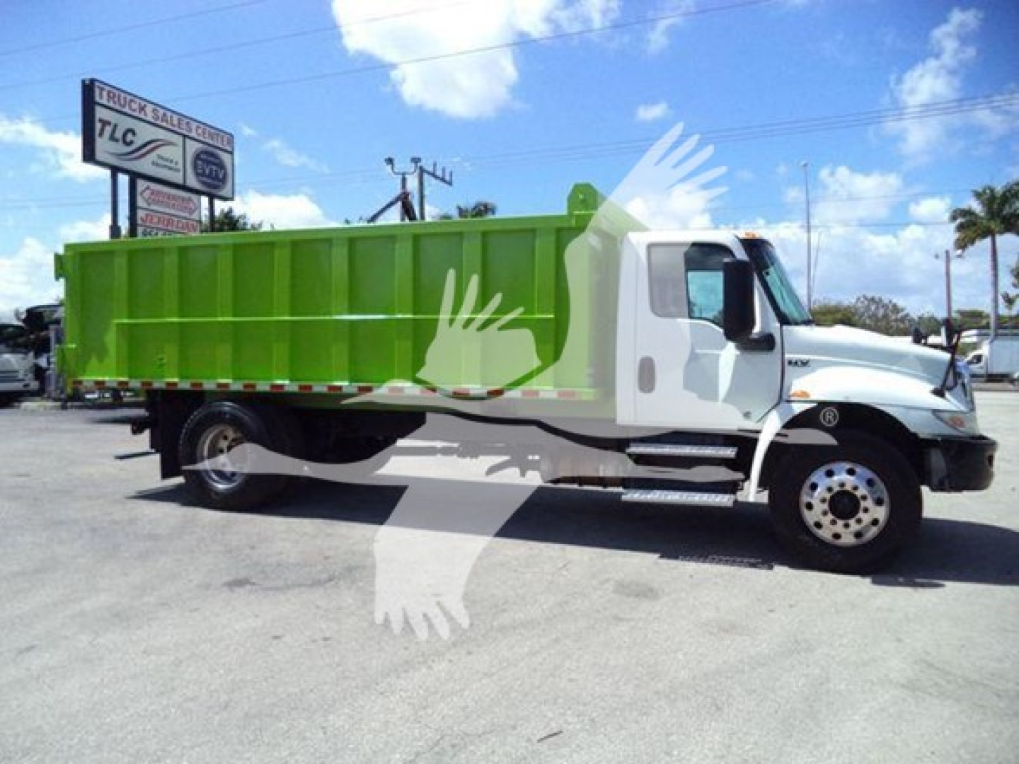 Truck body side view showing a green dump bed on a white cab with black wheels; background includes a sign and a palm tree; the image includes a watermark of a crane.
