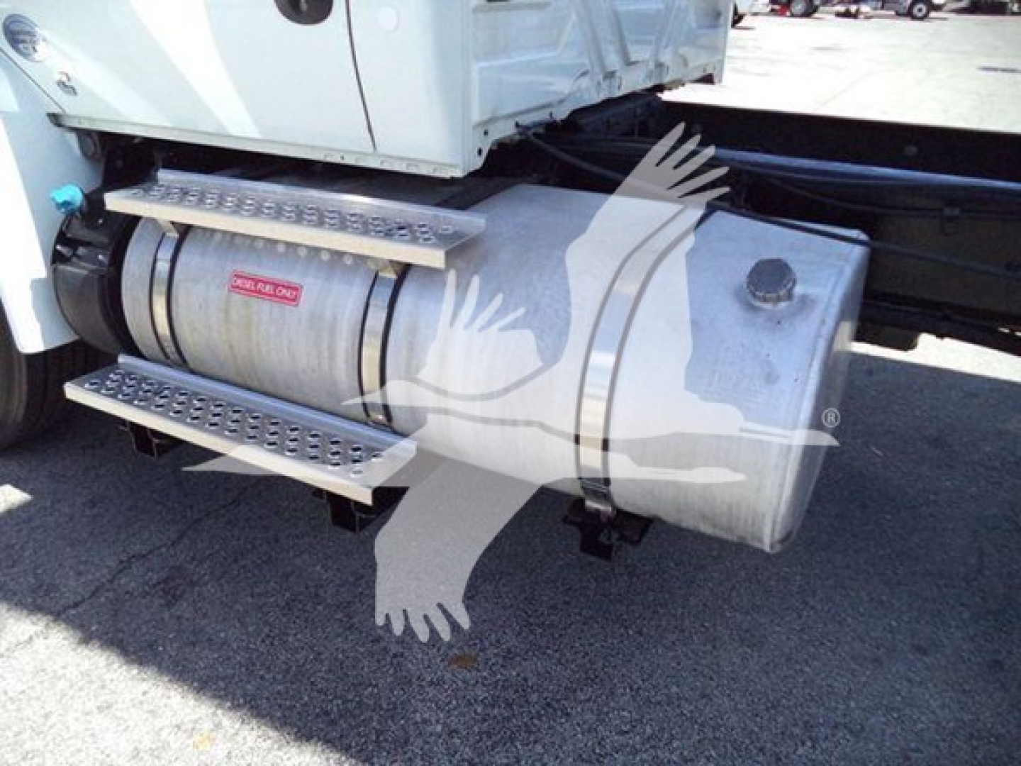 Vehicle fuel tank with steps on side of International MV dump truck showing a metal cylindrical tank with a label and a platform step. 