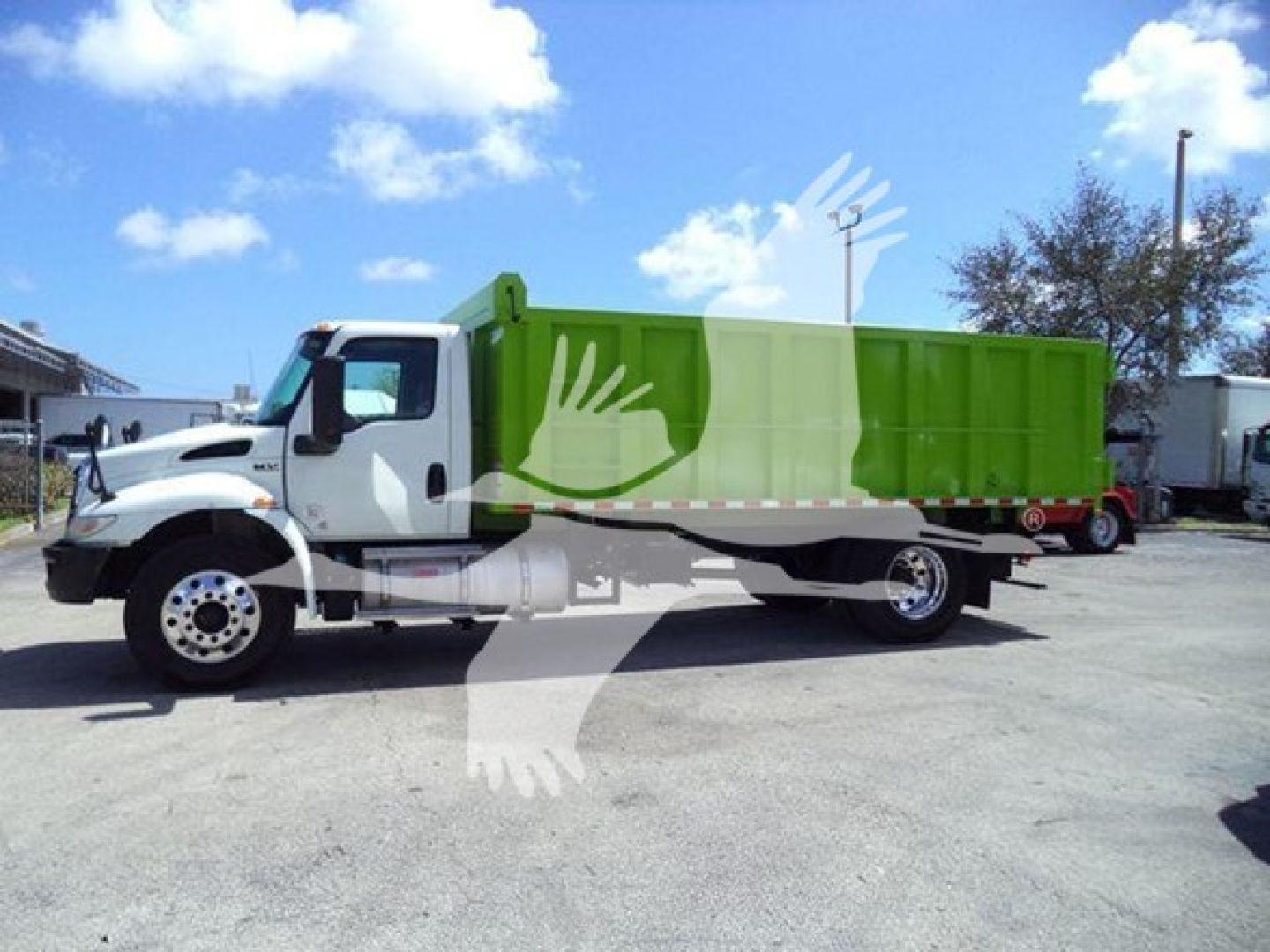 Dump truck side view showing a white cab and green dump body, International MV model, with stock T98791.