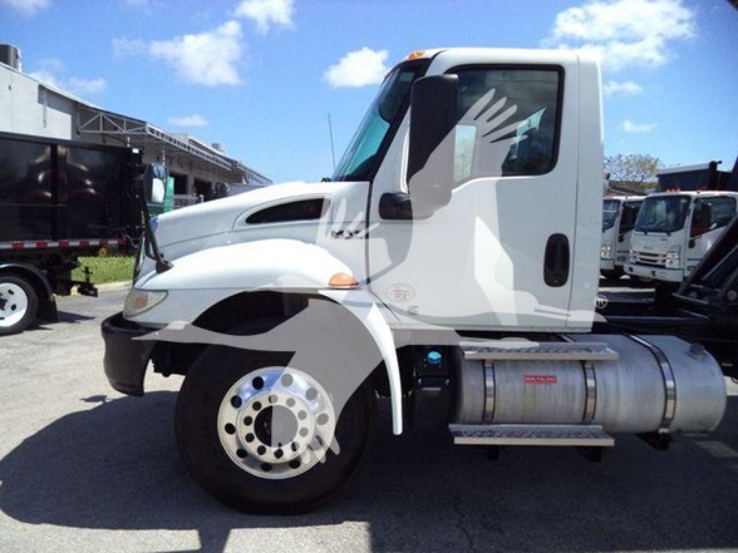Truck side view of a white 2020 International MV dump truck showing front wheel, cab, and dual fuel tanks with side step.