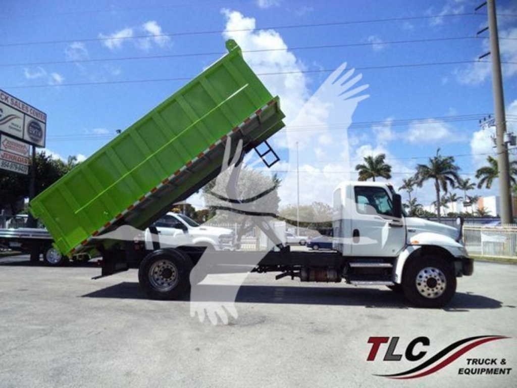 Dump truck with lime-green dump bed raised, side view showing cab and chassis, International MV model truck.
