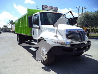 Dump truck front-left view with white cab and green dump body, VIN 3HAEUMML1LL198791 visible, dealership lot in background.