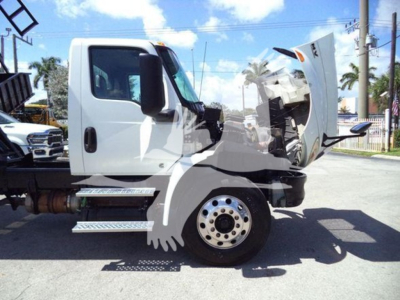 Truck cab with hood open showing engine area and front wheel; side view of a white 2020 International MV dump truck.