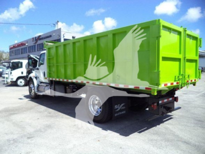 Truck bed side view of a bright green dump truck with white cab, showing a large dump body and rear wheels; no legible labels visible.