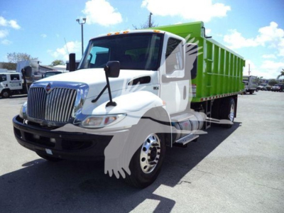 White and green 2020 International MV dump truck with green dump bed, front grille, and side mirrors visible in a parking lot.