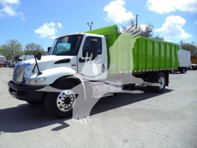 Dump truck showing engine bay and cab with white front and green dump body; International MV model with stock number T98791.