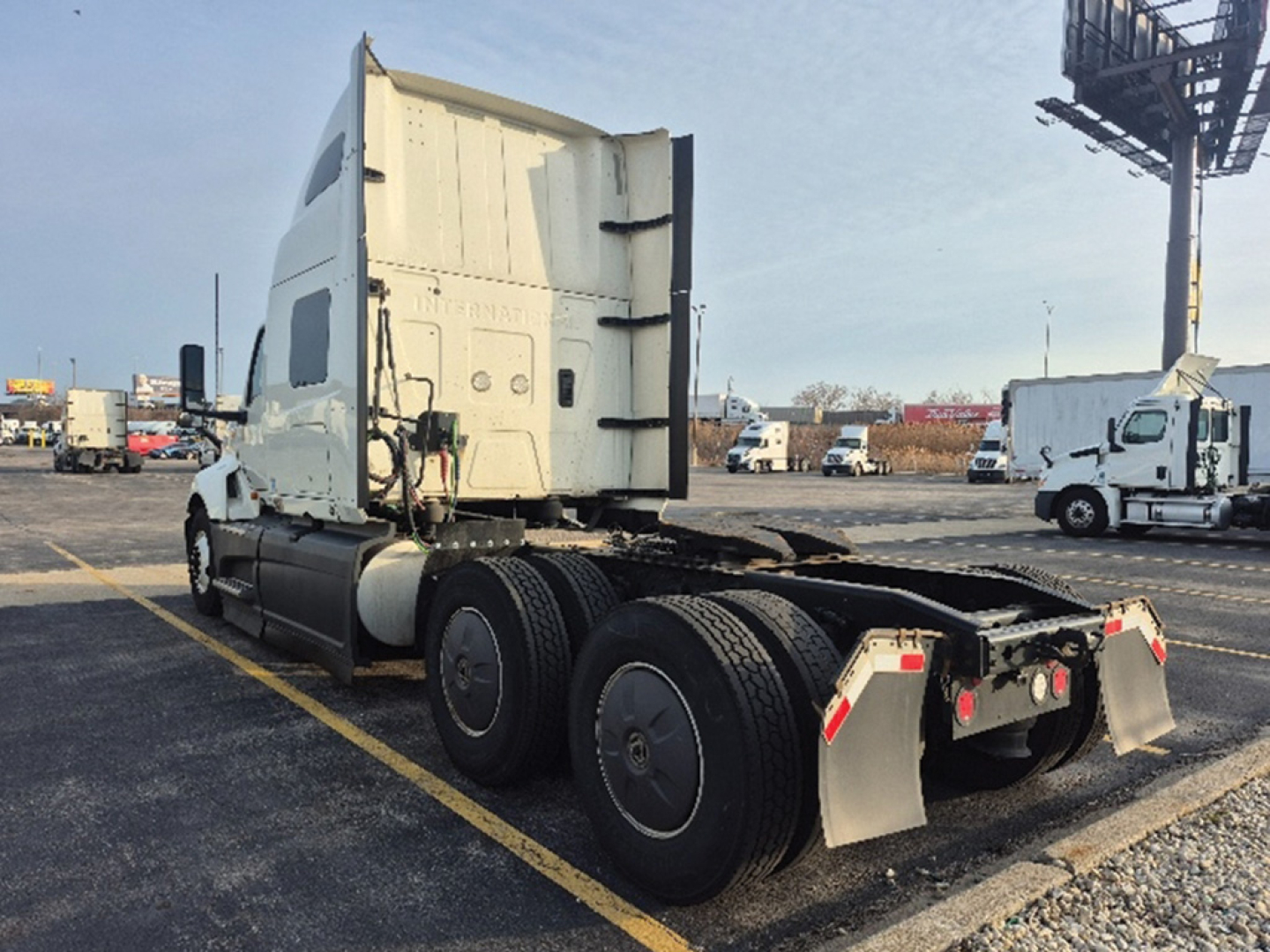 Truck cab and chassis of a 2023 International LT625, rear view showing fifth wheel area and dual rear axles with mudflaps and parking lot.